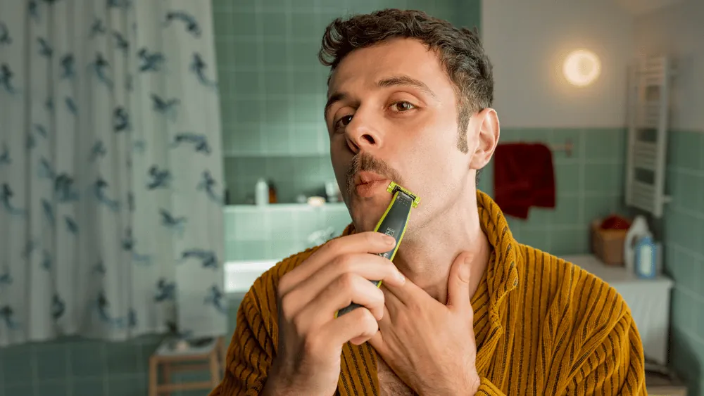 Një burrë që modelon mustaqet me Philips OneBlade